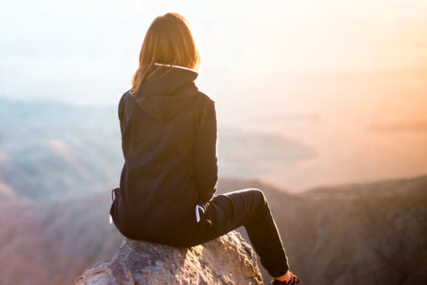 Jugendliche auf Fels sitzend im Gegenlicht